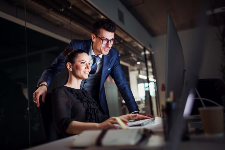 Young business people in an office at night, using computer.